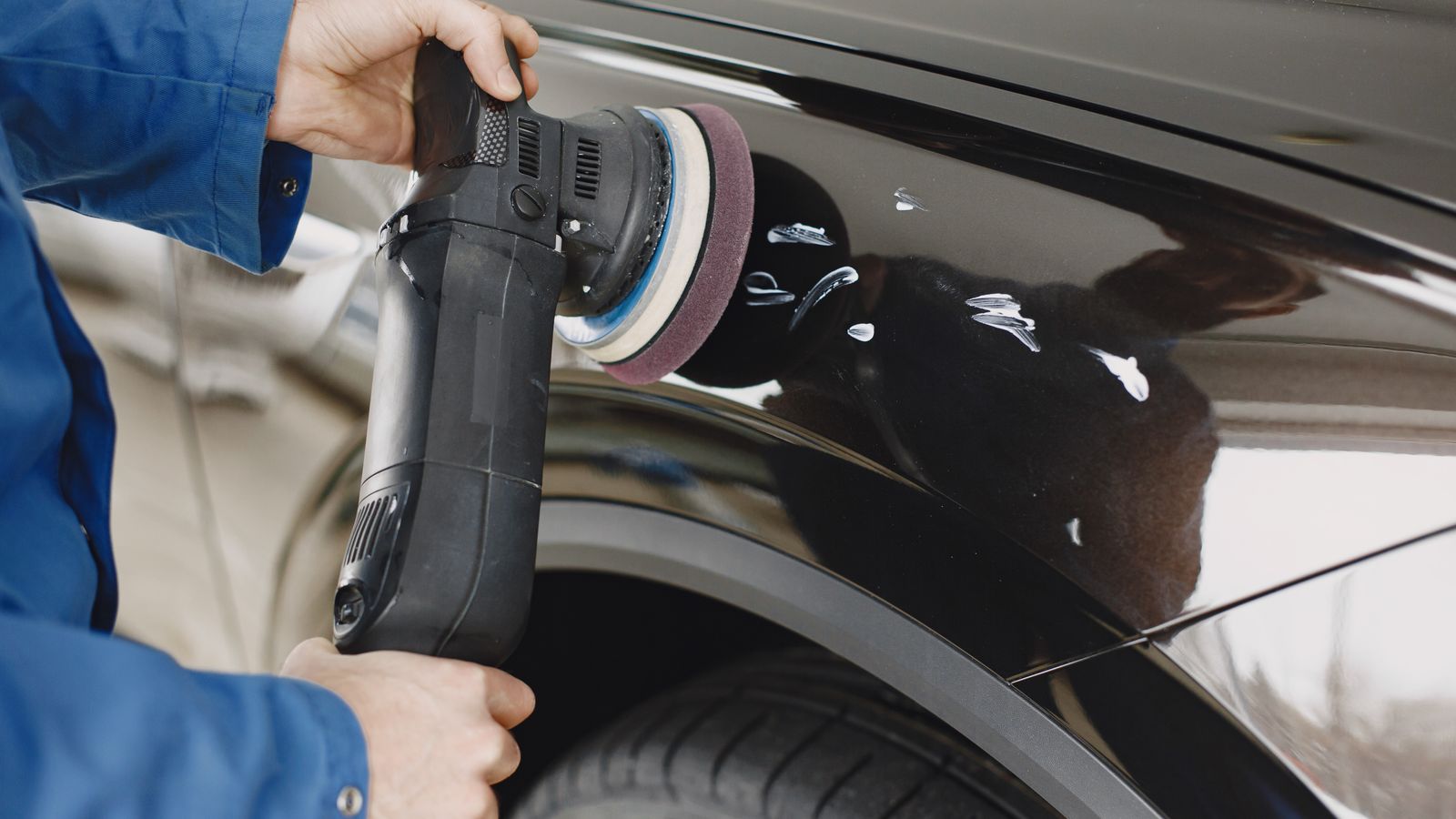 Hand applying car wax to a vehicle hood with an applicator pad