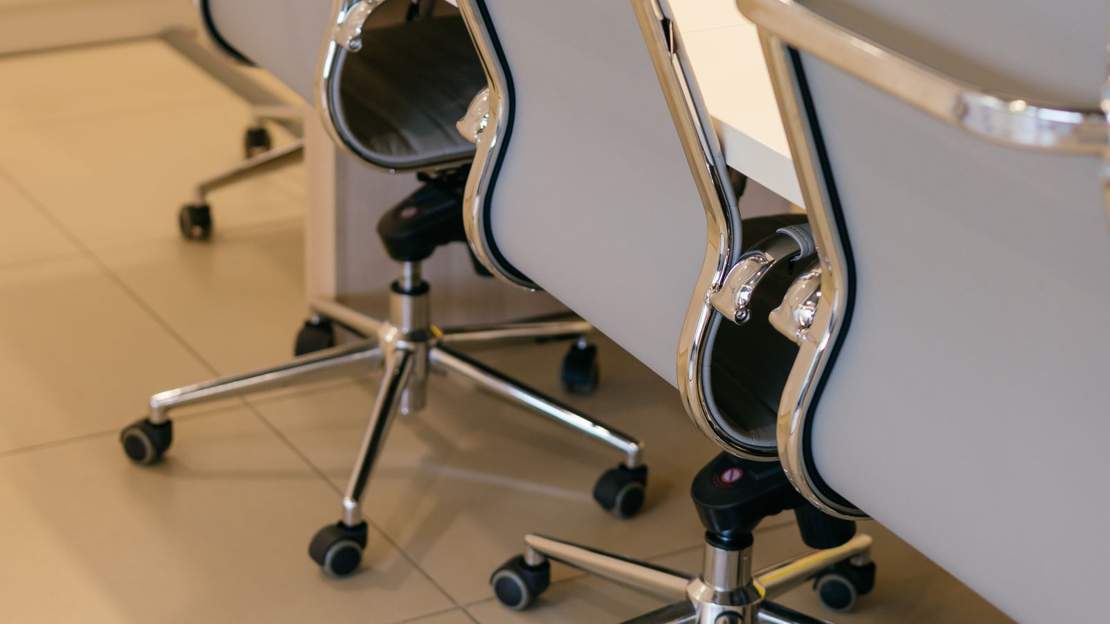 Person inspecting office chair wheels and casters near a hardwood floor