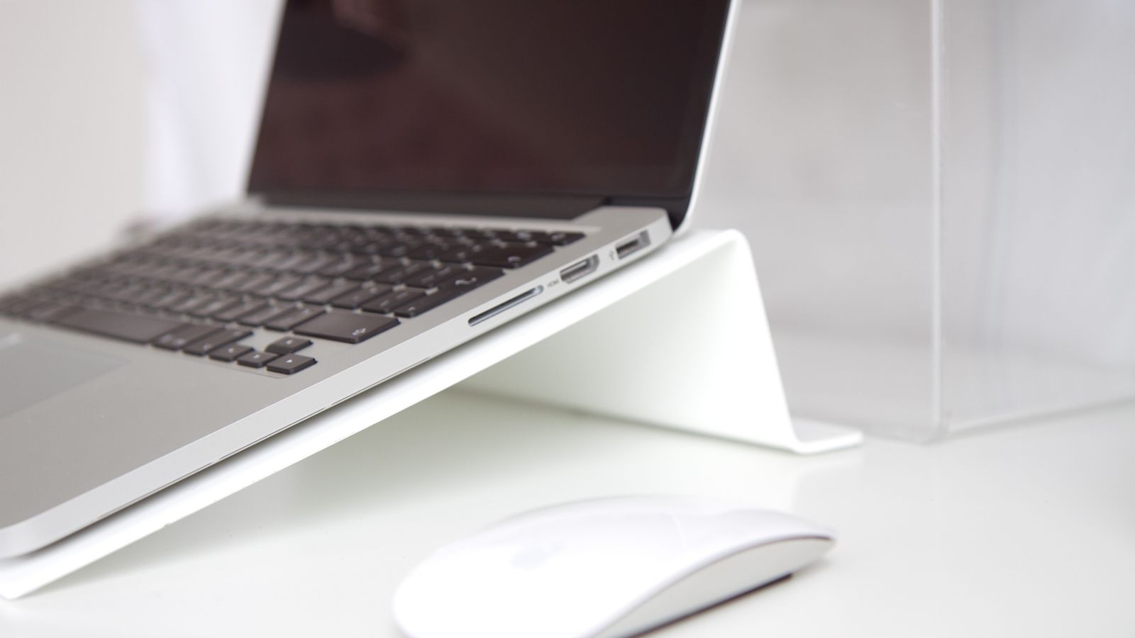 Laptop resting on a wooden desk riser stand in a bright home office