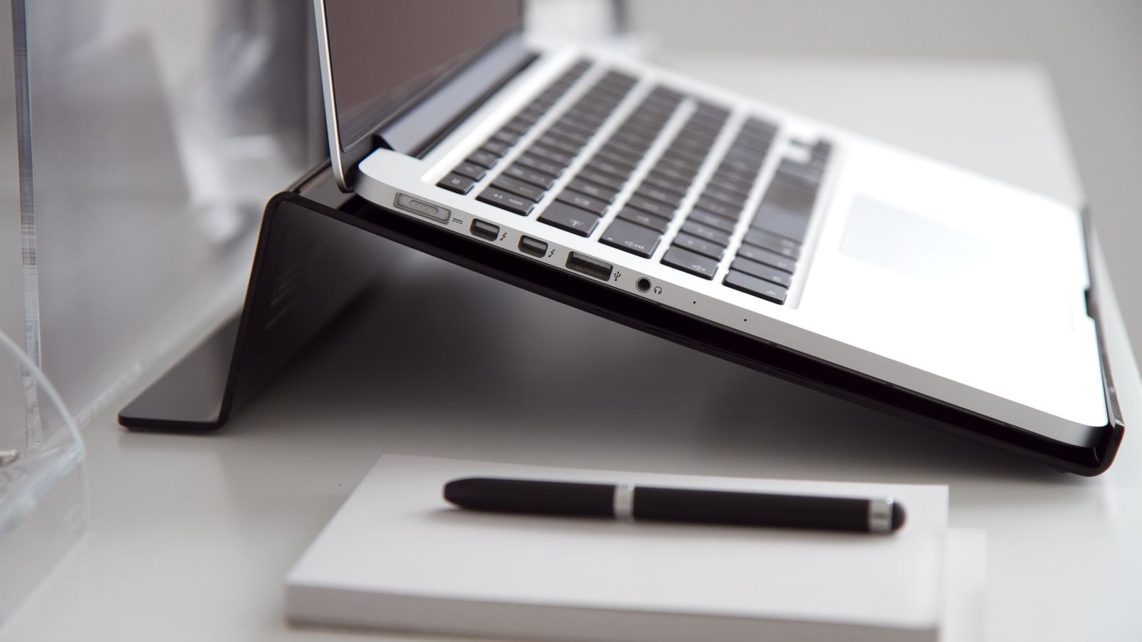 Close-up of hands wiping down a metal laptop stand with a microfiber cloth