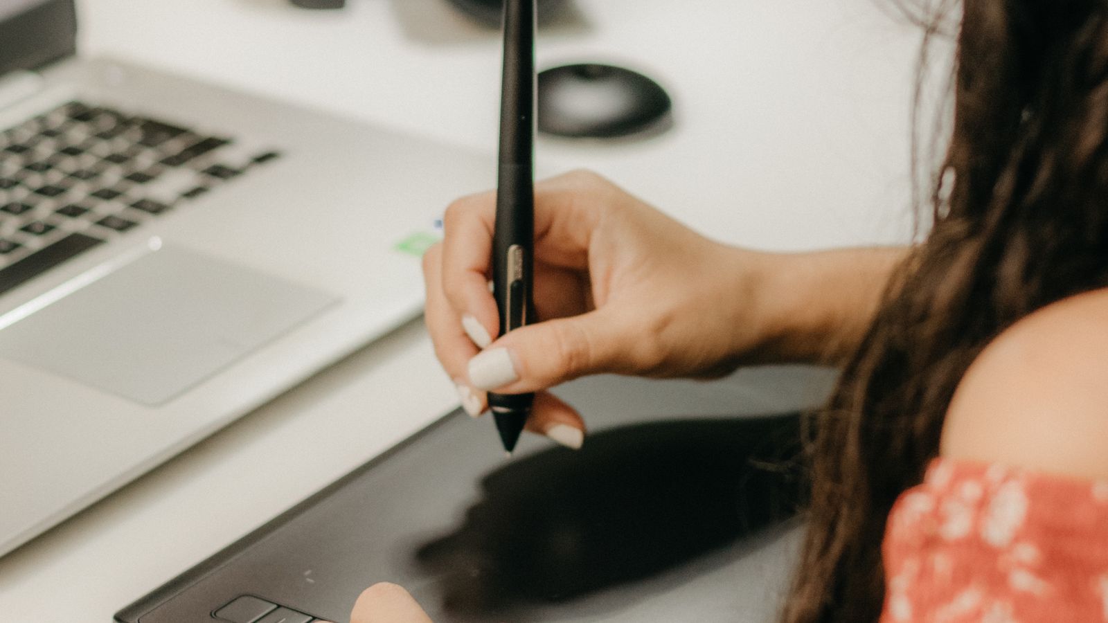 Close-up of a pen-style mouse resting on a desk next to a keyboard