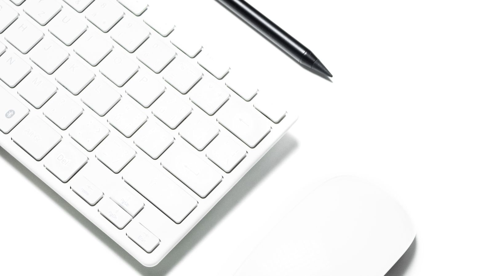 Hand cleaning a computer mouse and keyboard setup with a microfiber cloth