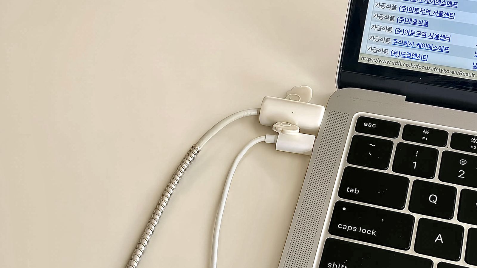 Close-up of a phone mounted on a desk edge with charging cable secured