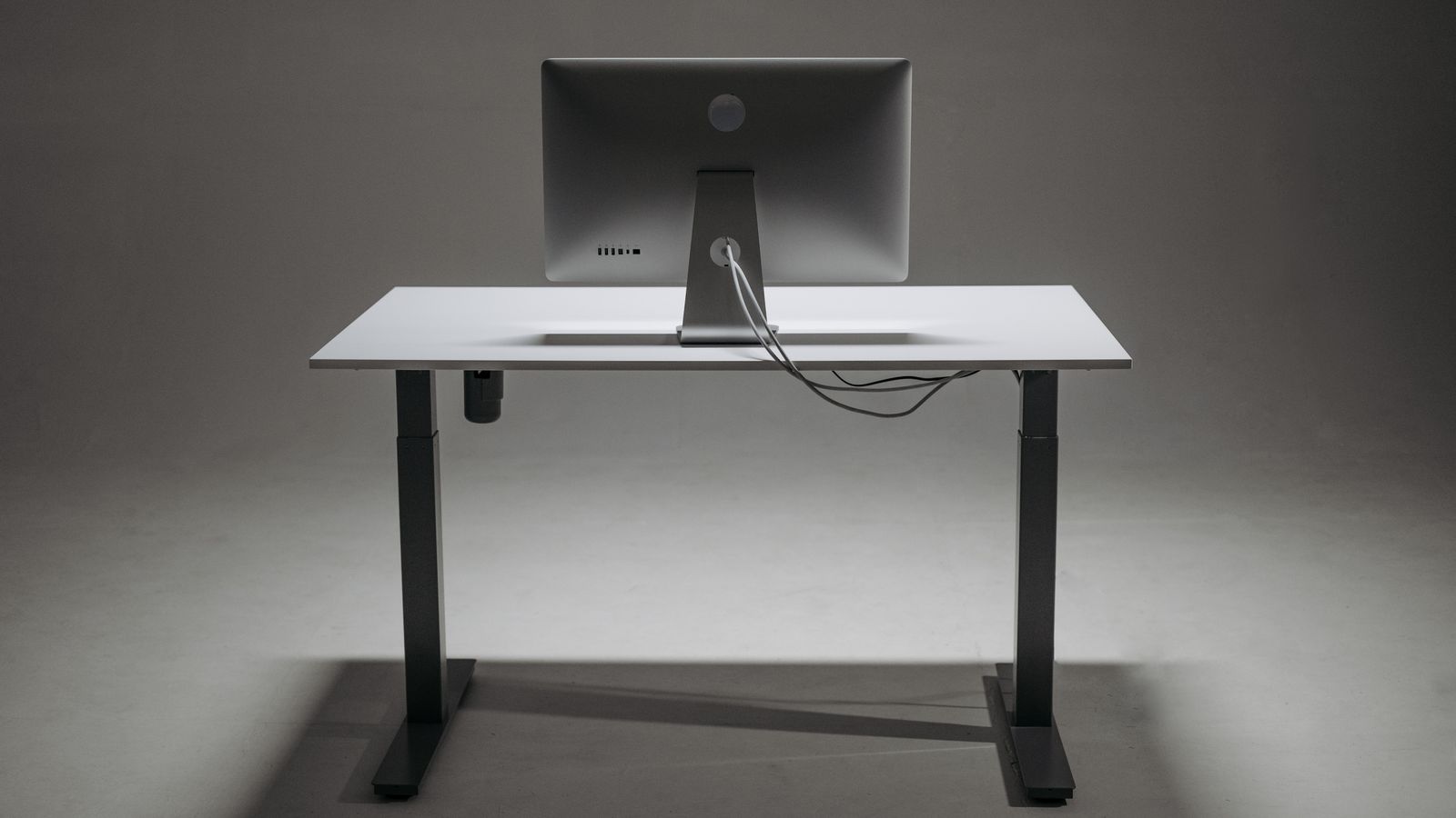 Standing desk with anti slip pad under the base and cables routed neatly along the leg