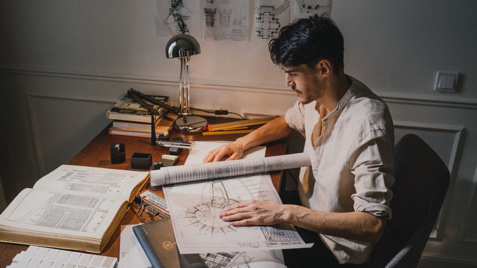 Architect reviewing blueprints on a large drafting desk in a bright studio
