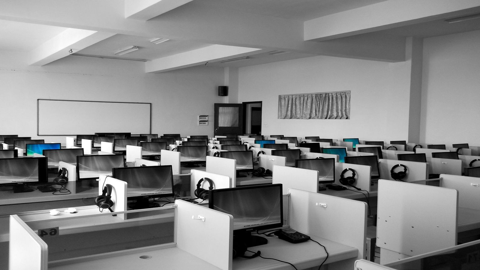 Rows of call center desks with computers and headsets in an open office