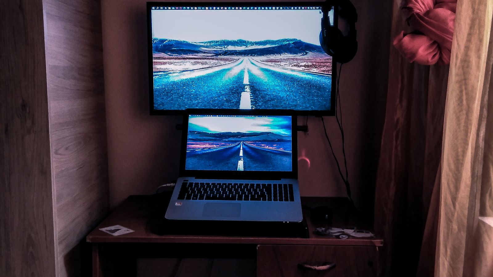 Person adjusting cables behind a single external monitor connected to a laptop