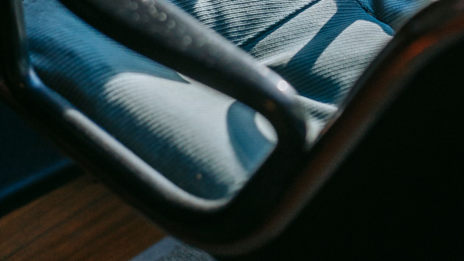 Person adjusting an ergonomic footstool height under a desk while seated in an office chair