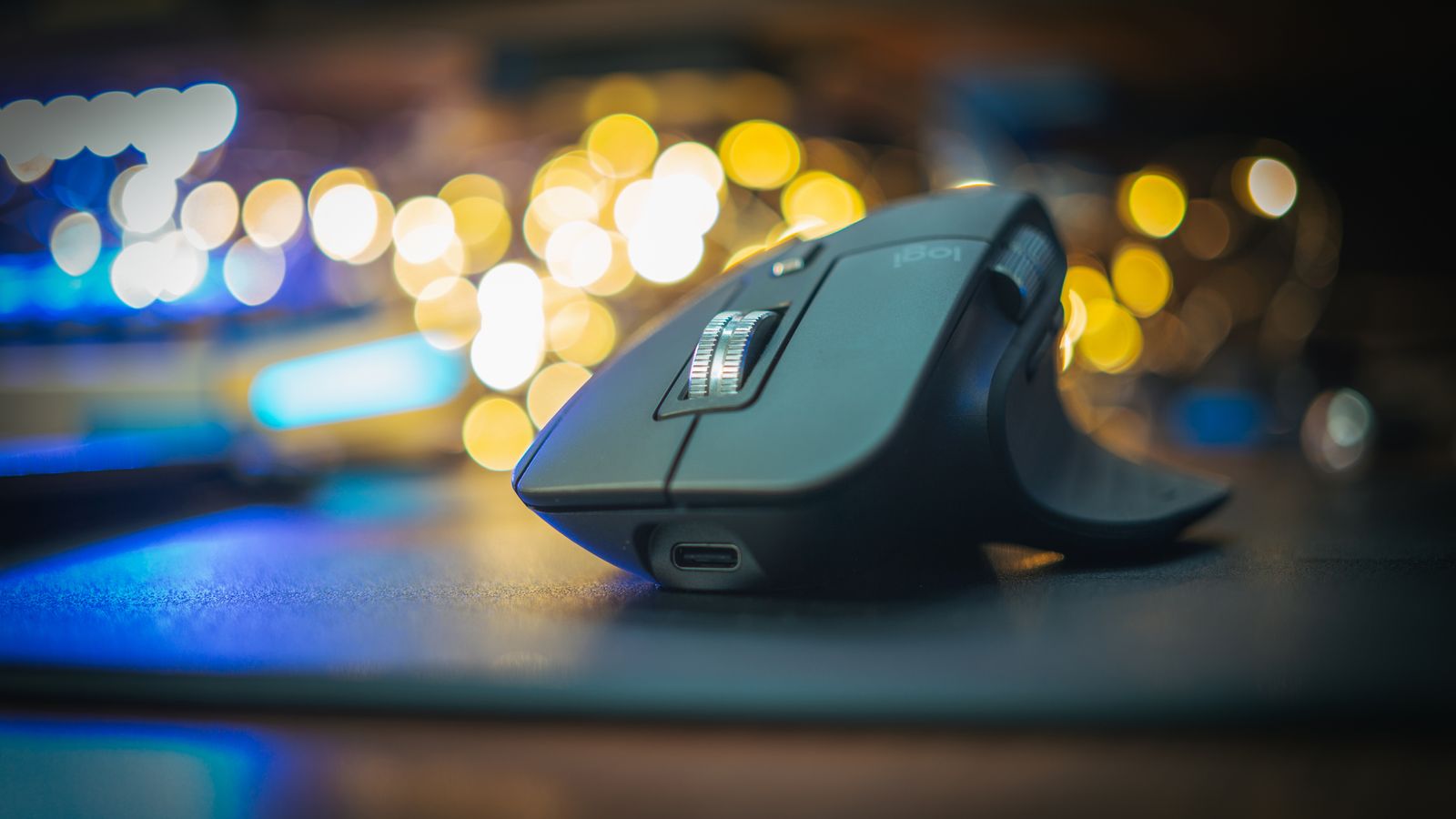 Finger trackball mouse with thumb resting near the scroll wheel on a desk