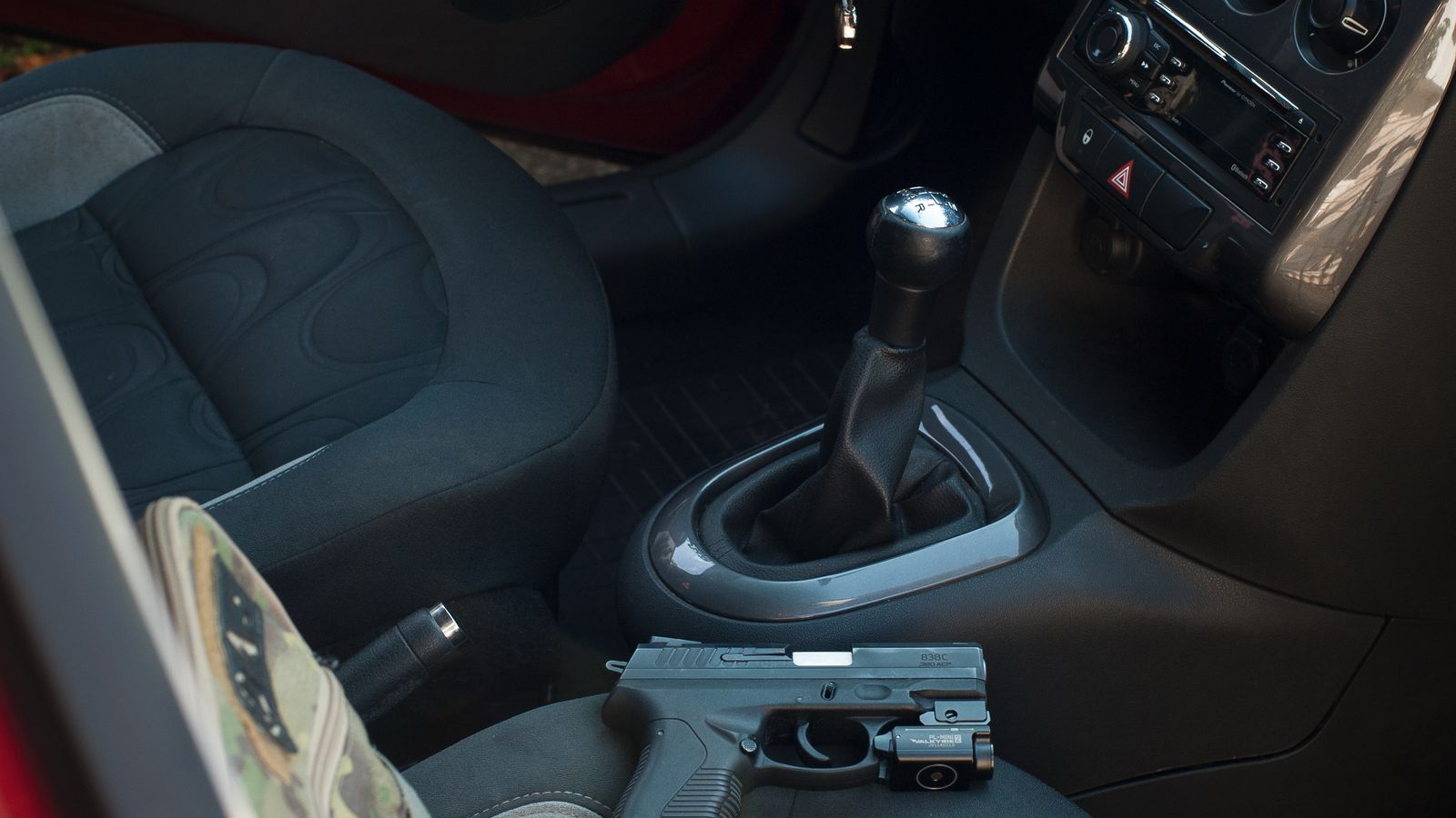 Compact car trash can mounted near the center console of a vehicle interior
