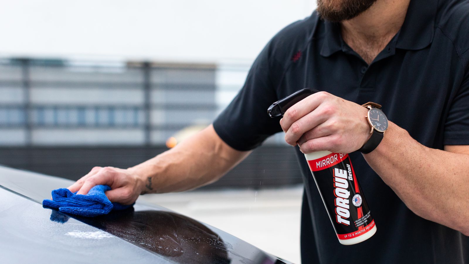 Close-up of a microfiber towel buffing wax to a glossy shine on a car's fender