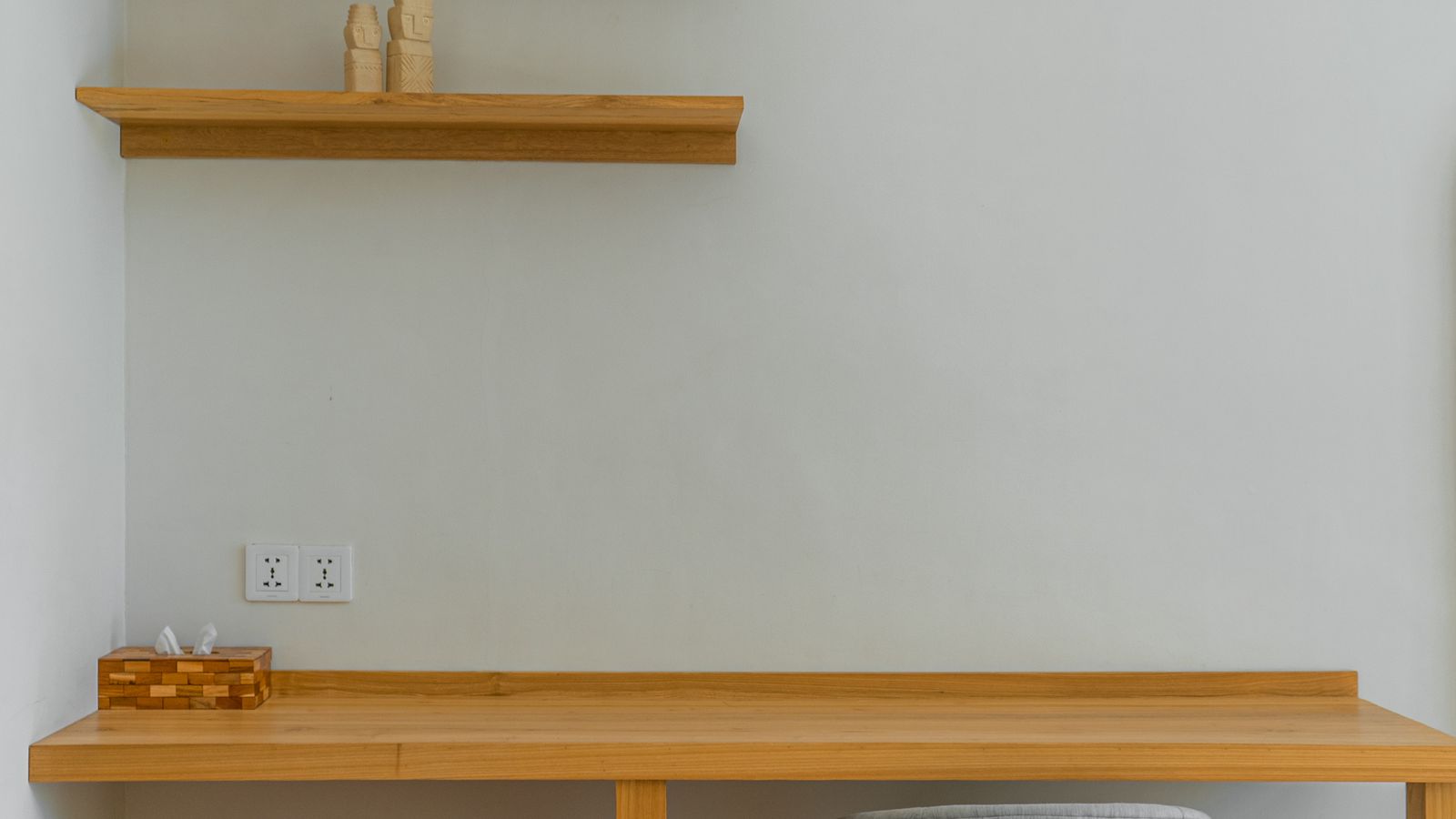 Minimalist wooden floating desk mounted on a wall in a small home office