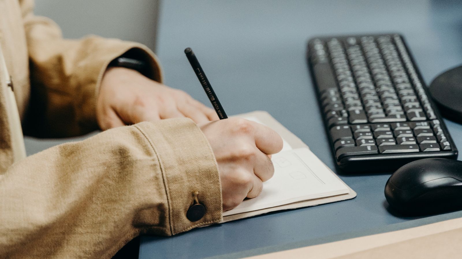 Close-up of hands typing on a keyboard positioned on an adjustable under-desk tray