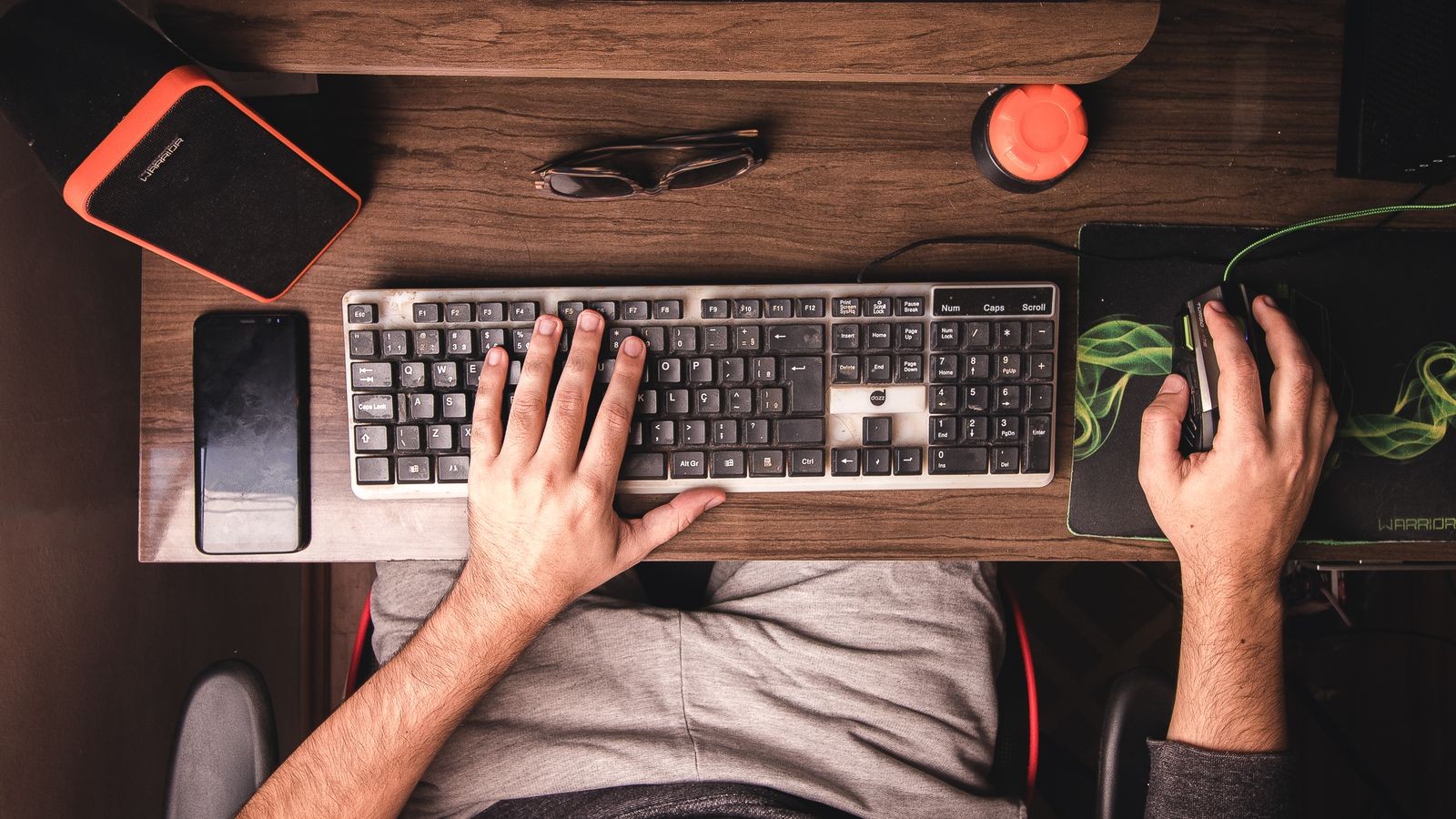 Person adjusting the height of a sliding keyboard tray under a home office desk