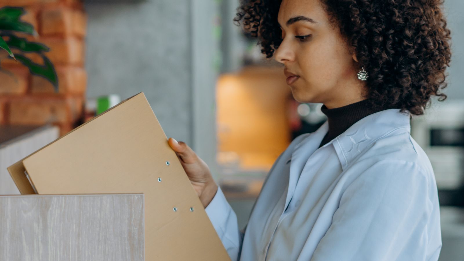 Person organizing labeled folders and reviewing documents beside an office storage cabinet