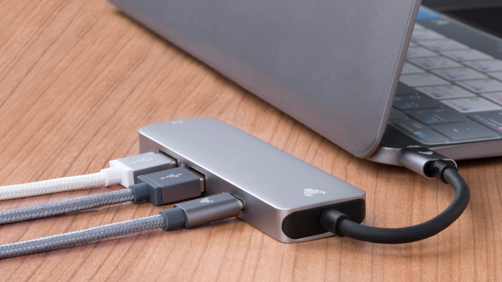 Close-up of a laptop docking hub with multiple cables connected on a wooden desk