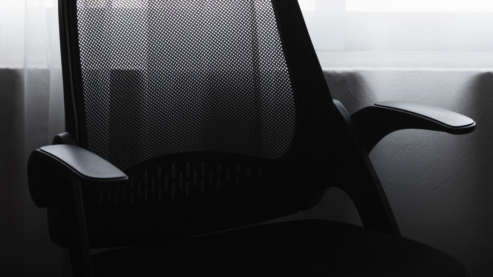 Person comparing a mesh-back office chair at a home workstation