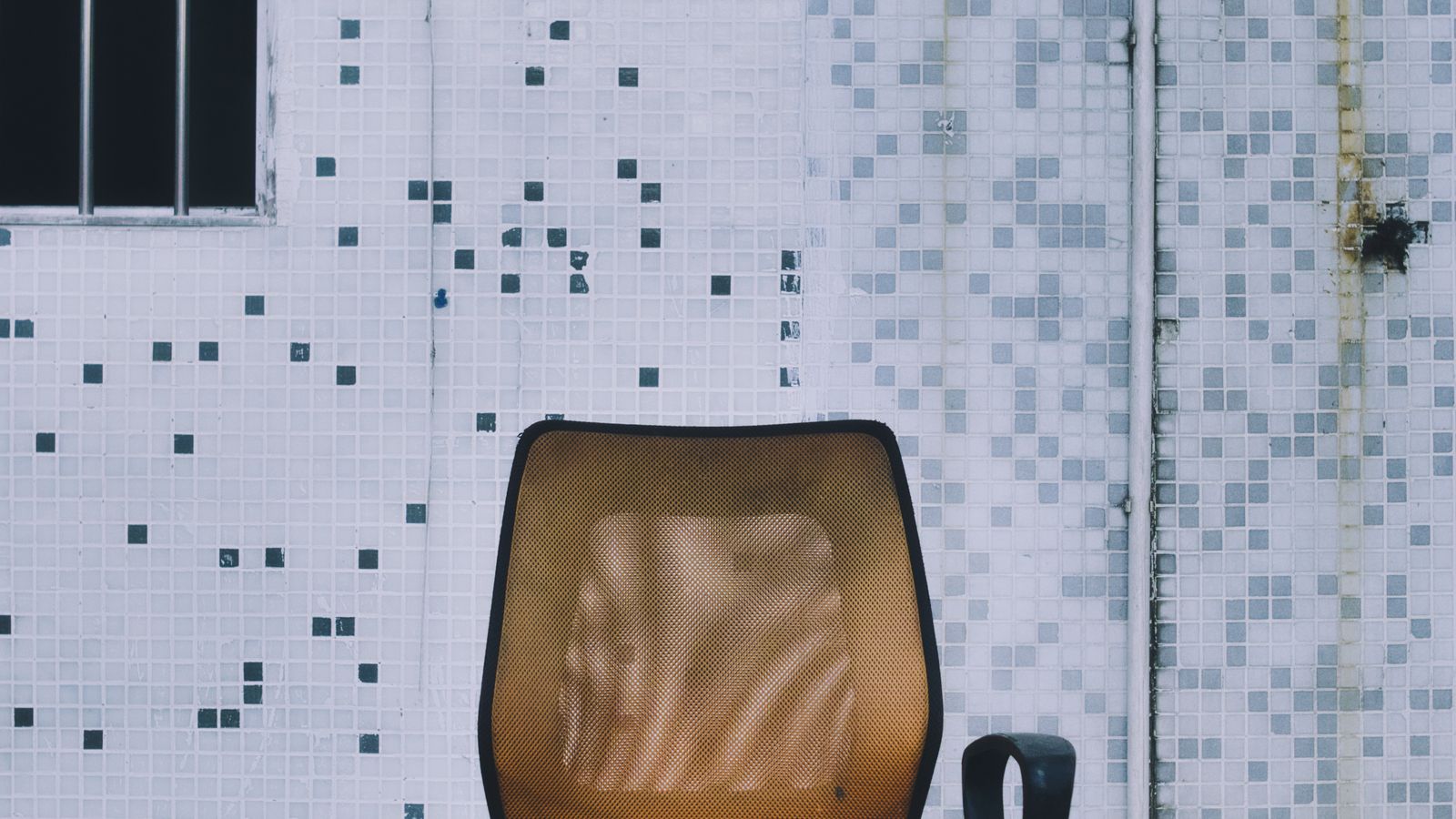 Person adjusting the height and recline of an office chair with a mesh back