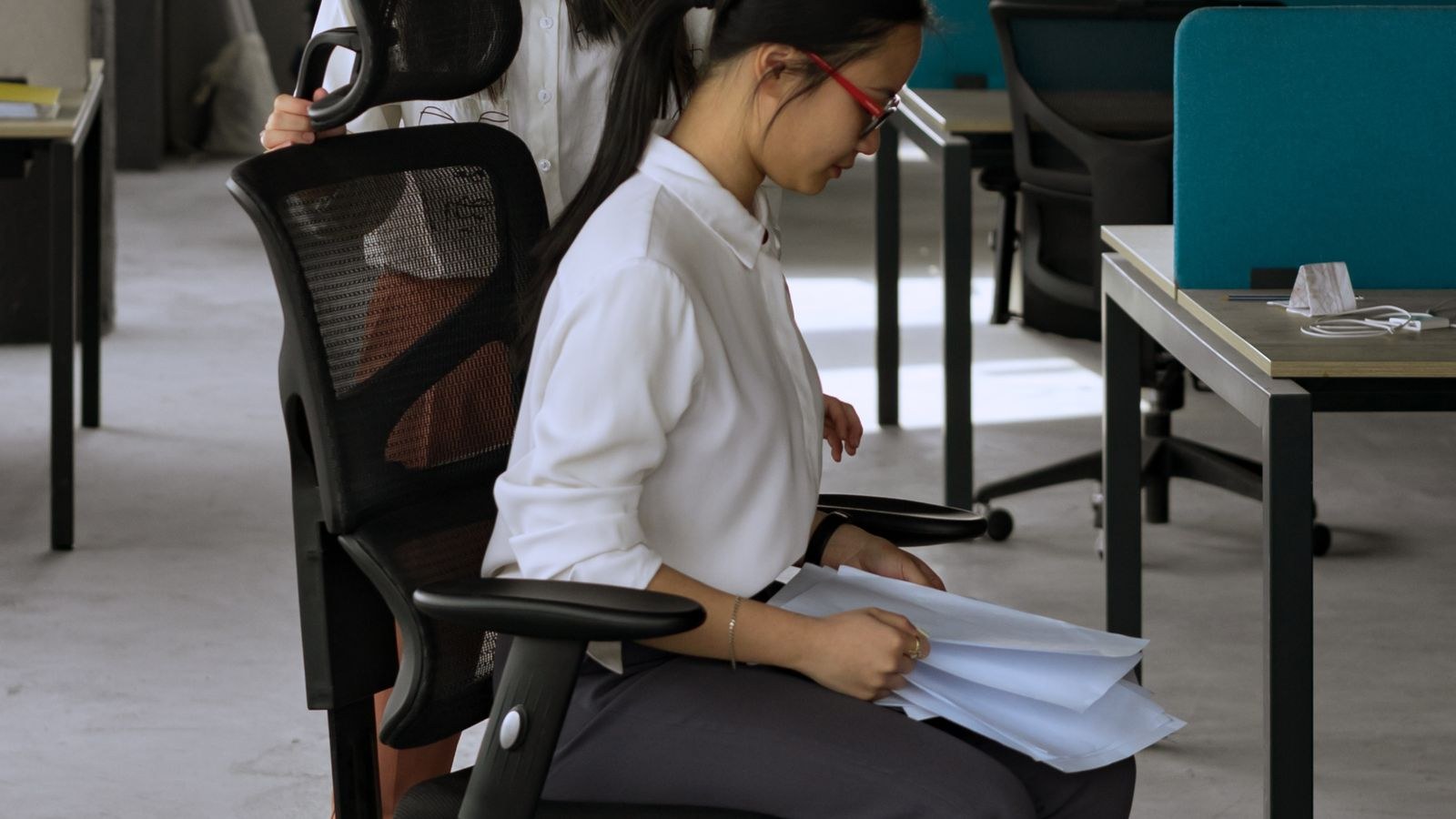 Person adjusting recline tension knob on an office chair suited for herniated disc support