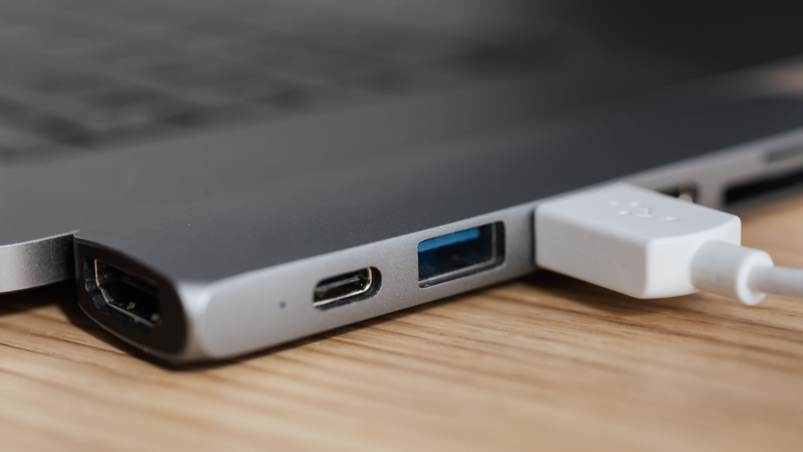 Laptop raised on a stand and connected to a docking station on a home office desk