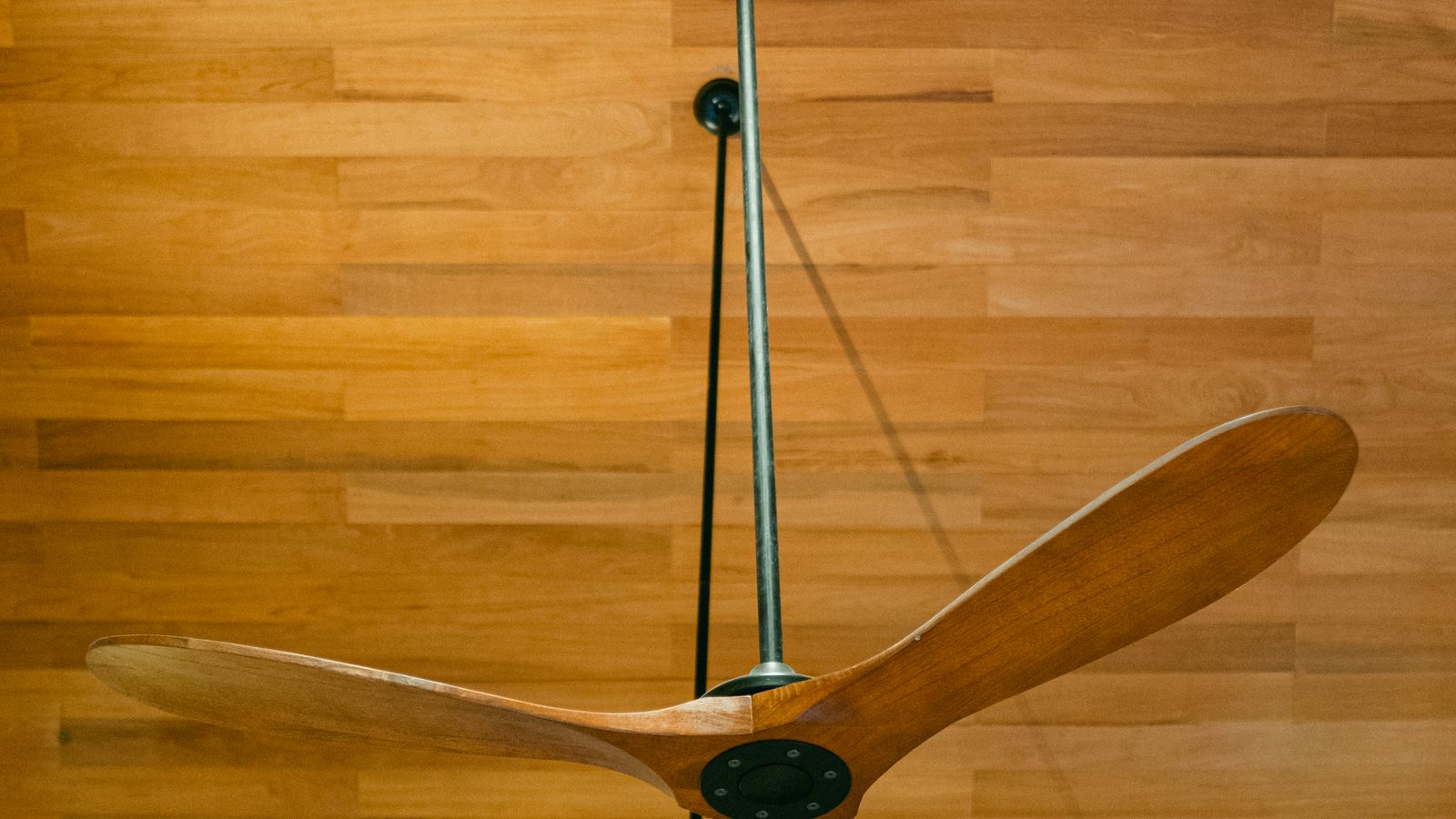 Wooden blade outdoor ceiling fan mounted on a covered patio ceiling