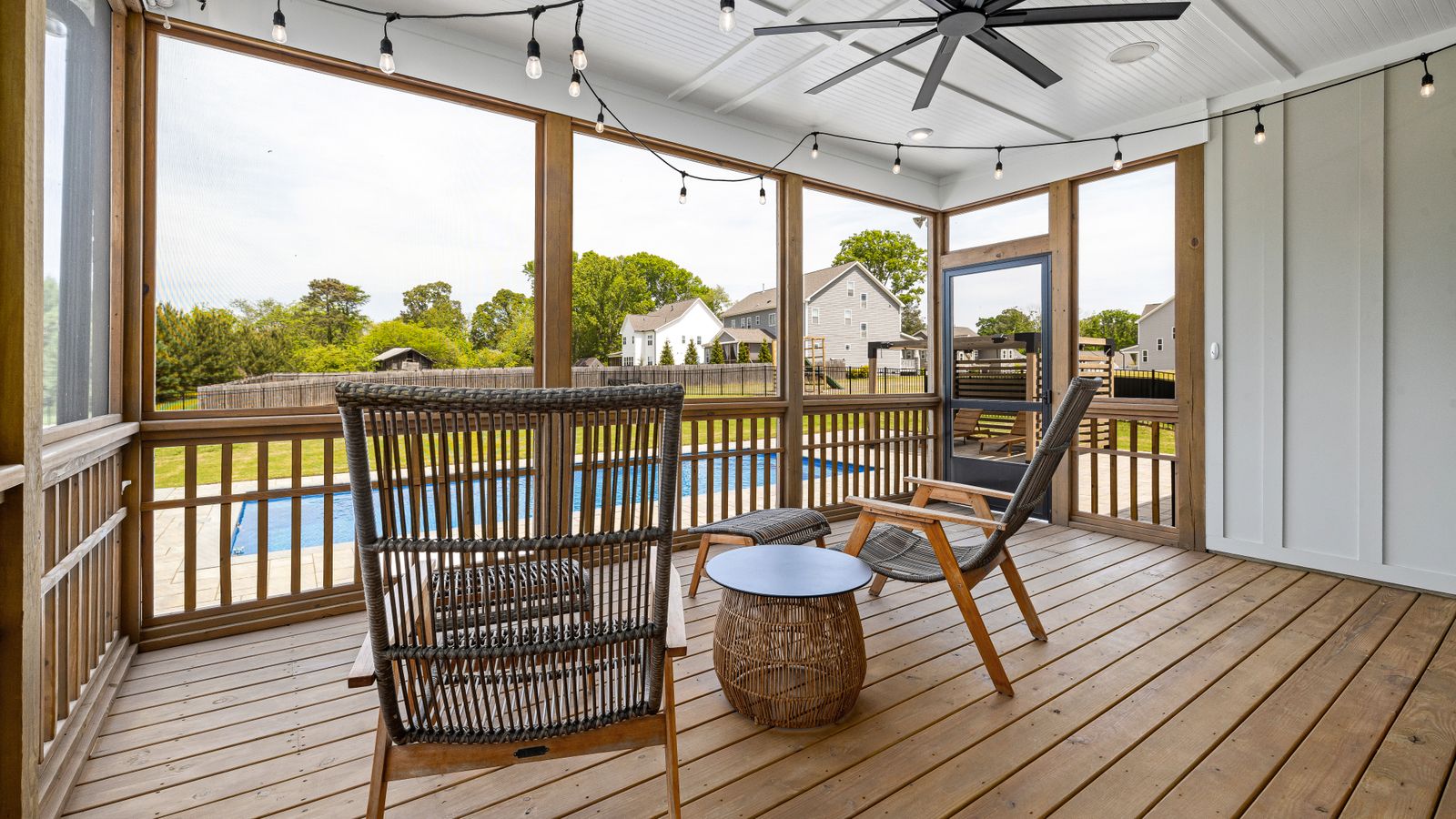 Covered outdoor patio lounge area where a ceiling fan helps circulate air near a seating and pool space