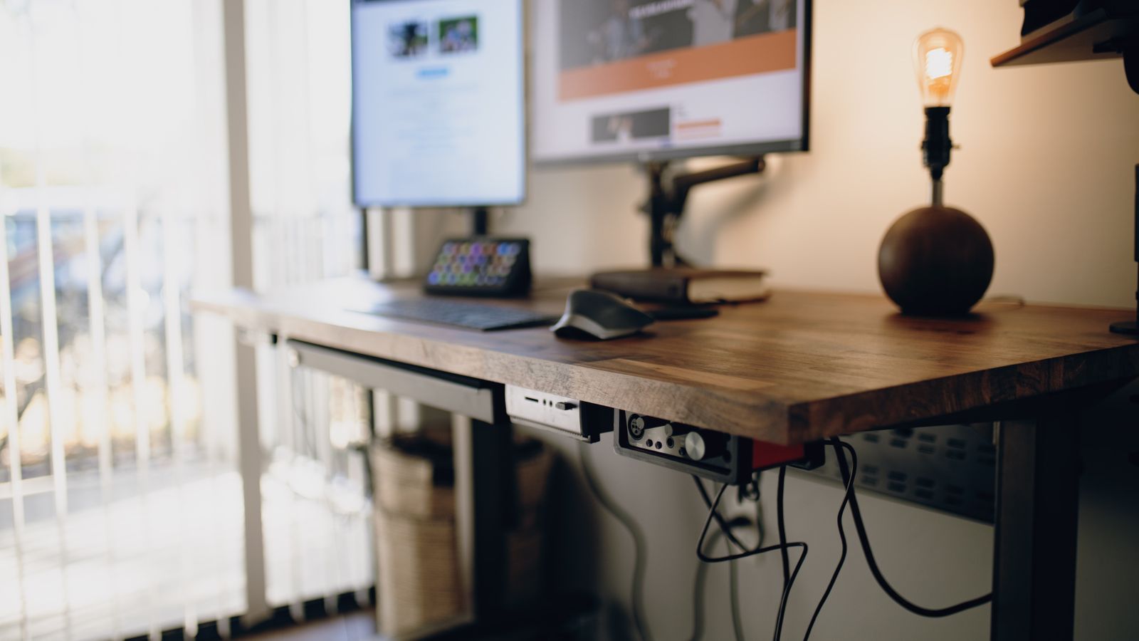 Close-up of under-desk cable management tray keeping power cords and charging cables organized