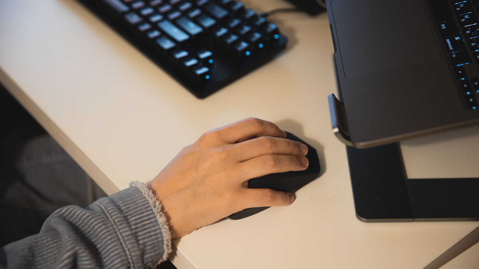 Person typing on an ergonomic keyboard next to a trackball mouse at a desk setup