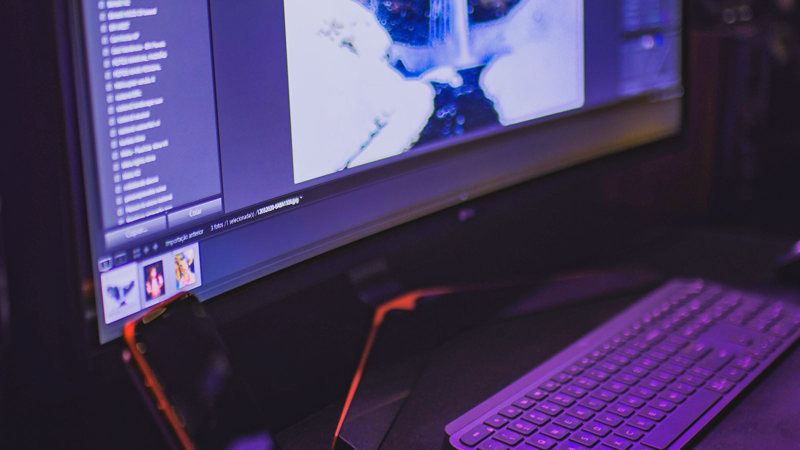 Close-up of an ultrawide monitor and keyboard on a clean desk showing screen glare and reflection