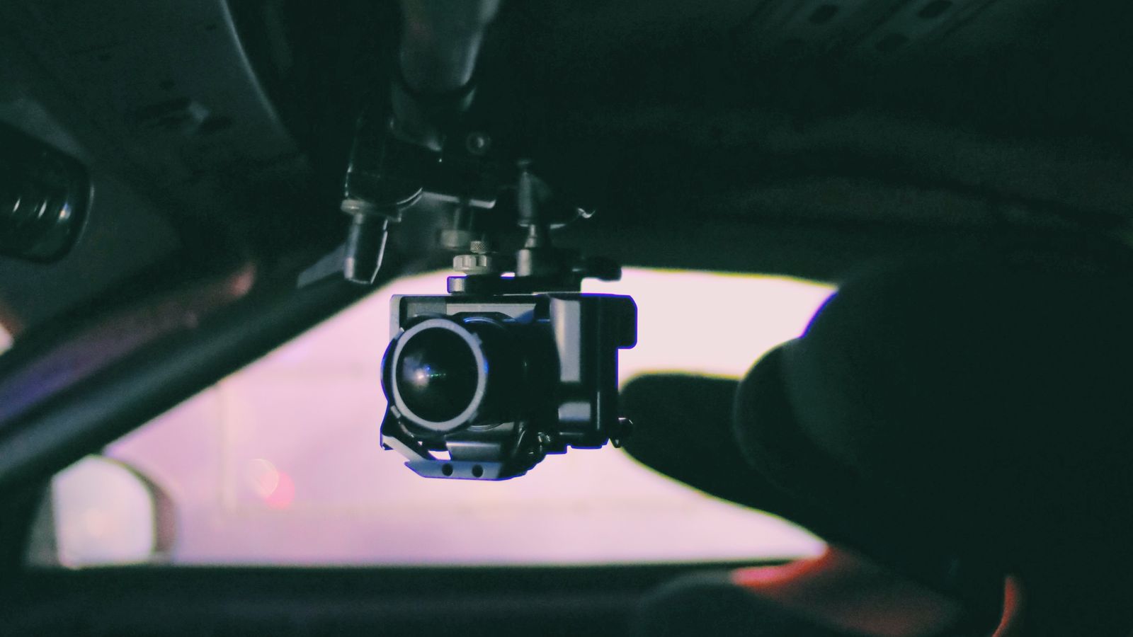 Compact dash camera mounted on a car windshield recording the road ahead