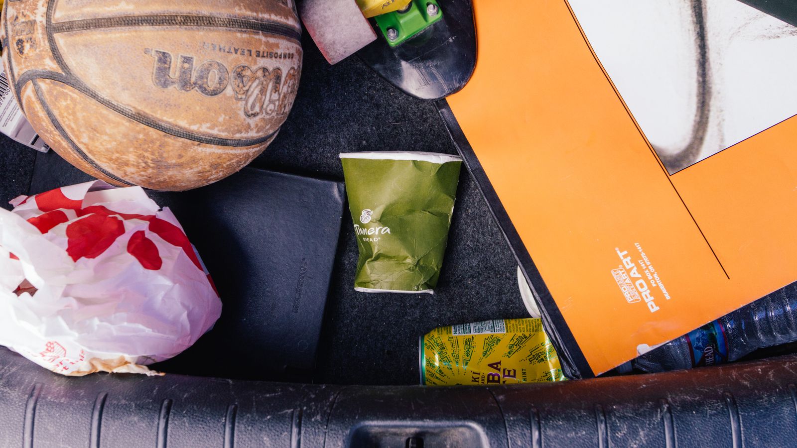 Trash and clutter accumulated in a car interior before adding a dedicated trash can